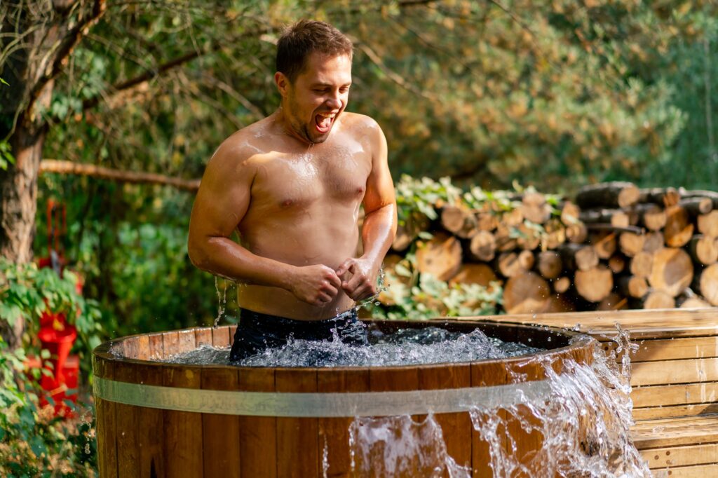 athletic smiling man relaxing in cold water in an outdoor swimming pool in nature in the woods